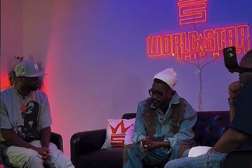 Beenie Man seated for an interview at the WorldStar Hip Hop studio, under the WorldStar neon sign
