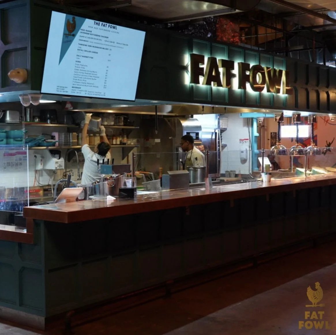 The Fat Fowl food hall counter under an illuminated Fat Fowl sign, with the menu on a screen above the open kitchen