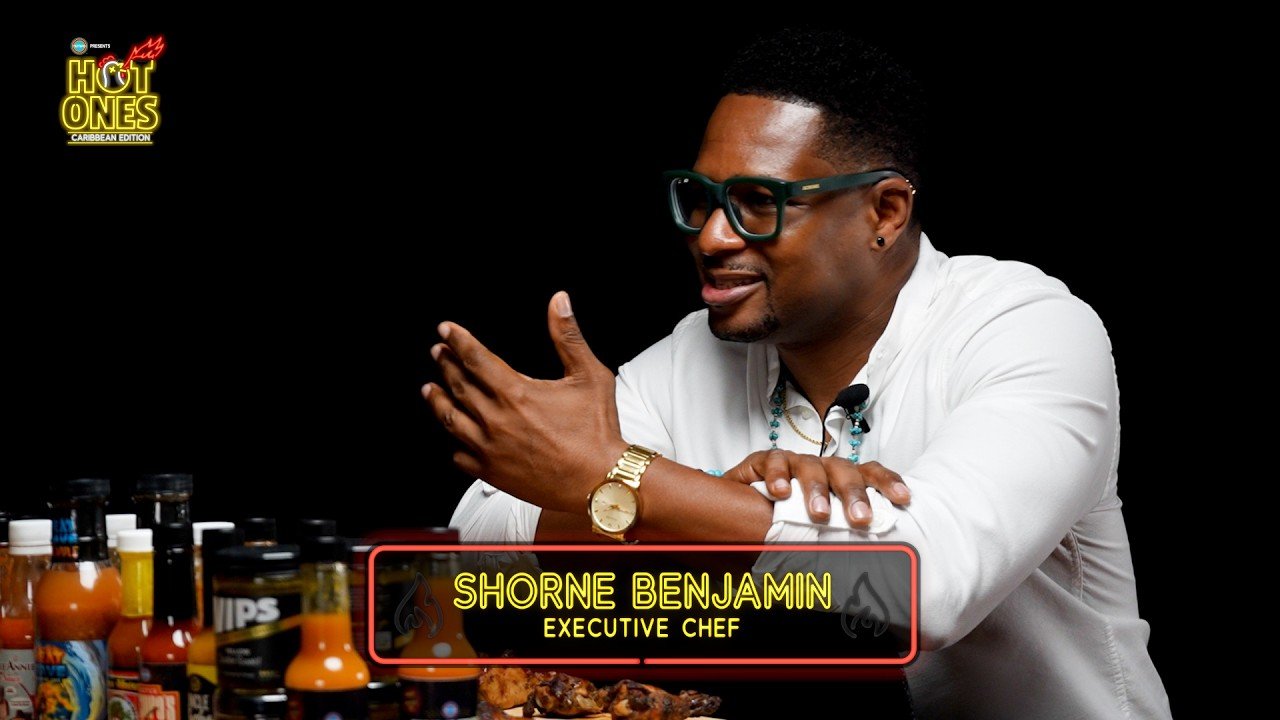 A guest at the Hot Ones Caribbean table with the lower third reading Shorne Benjamin, Executive Chef