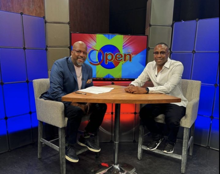 Two men seated at a table on the BronxNet OPEN studio set, the OPEN logo on the screen behind them