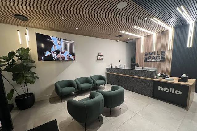The SmileSpace reception area with branded signage, a hello desk and green seating